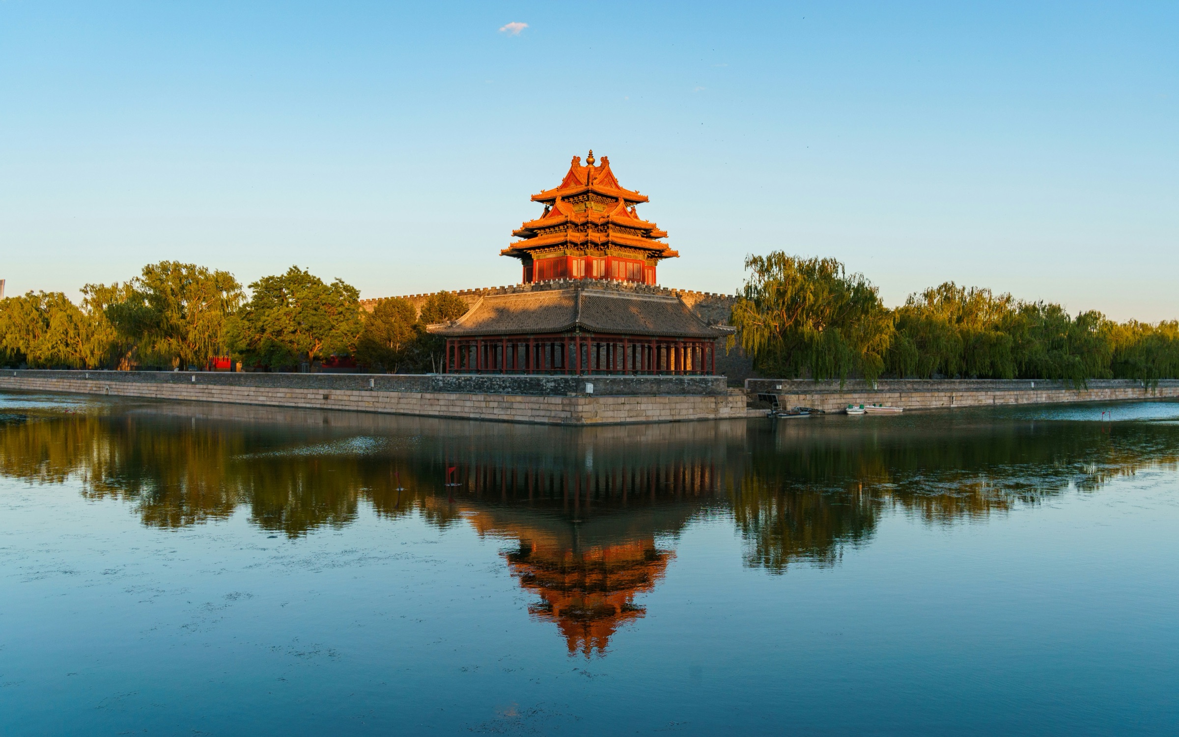The corner tower of the Forbidden City reflected in its moat at golden hour