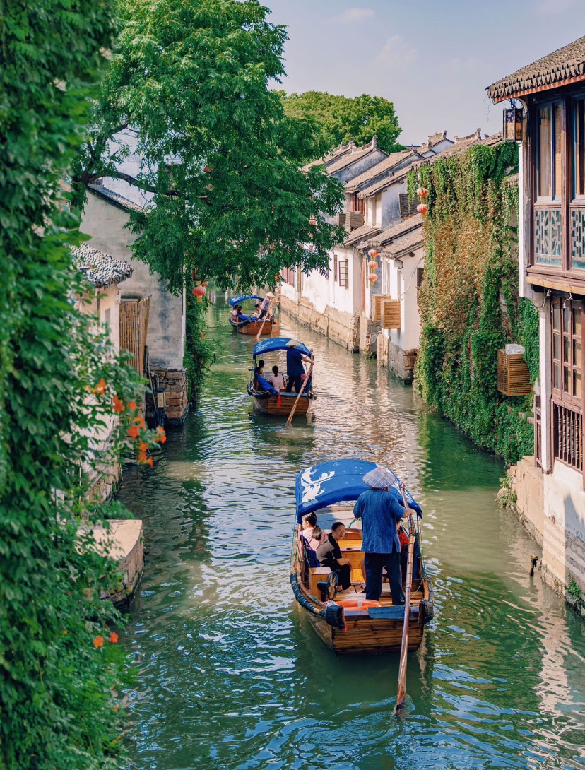 Wooden boats drifting along a willow-lined canal in a Jiangnan water town